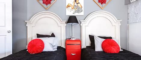 A hotel room with two beds, a red dresser, and artwork on the wall.