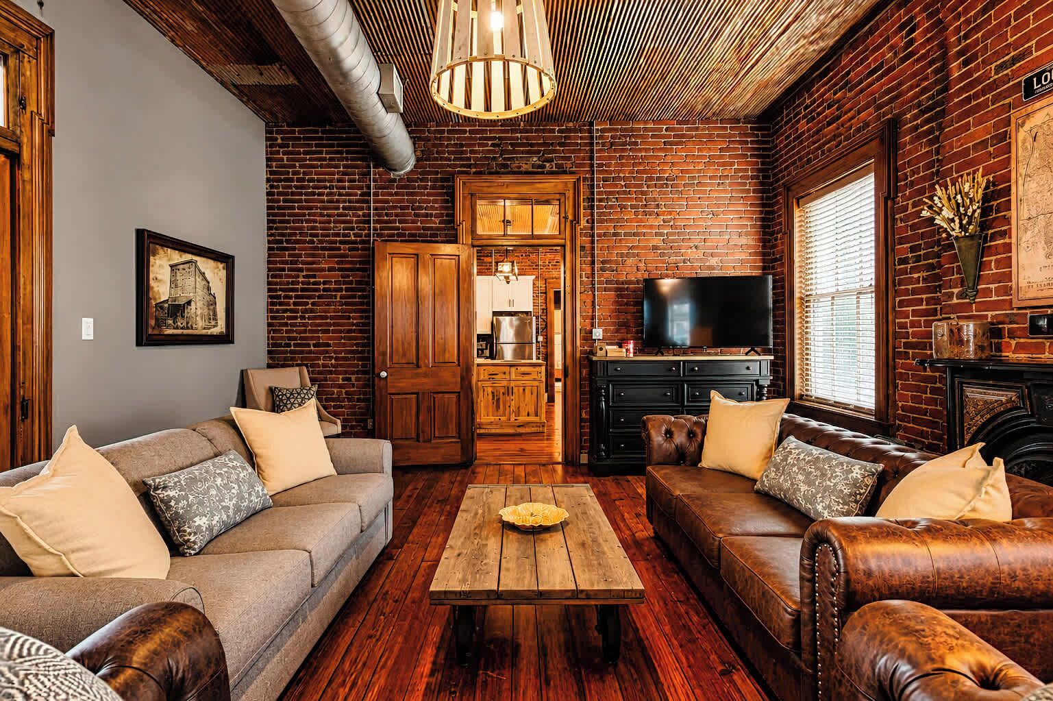 Una sala de estar acogedora con chimenea, sofás de cuero, una mesa de centro de madera y un televisor.