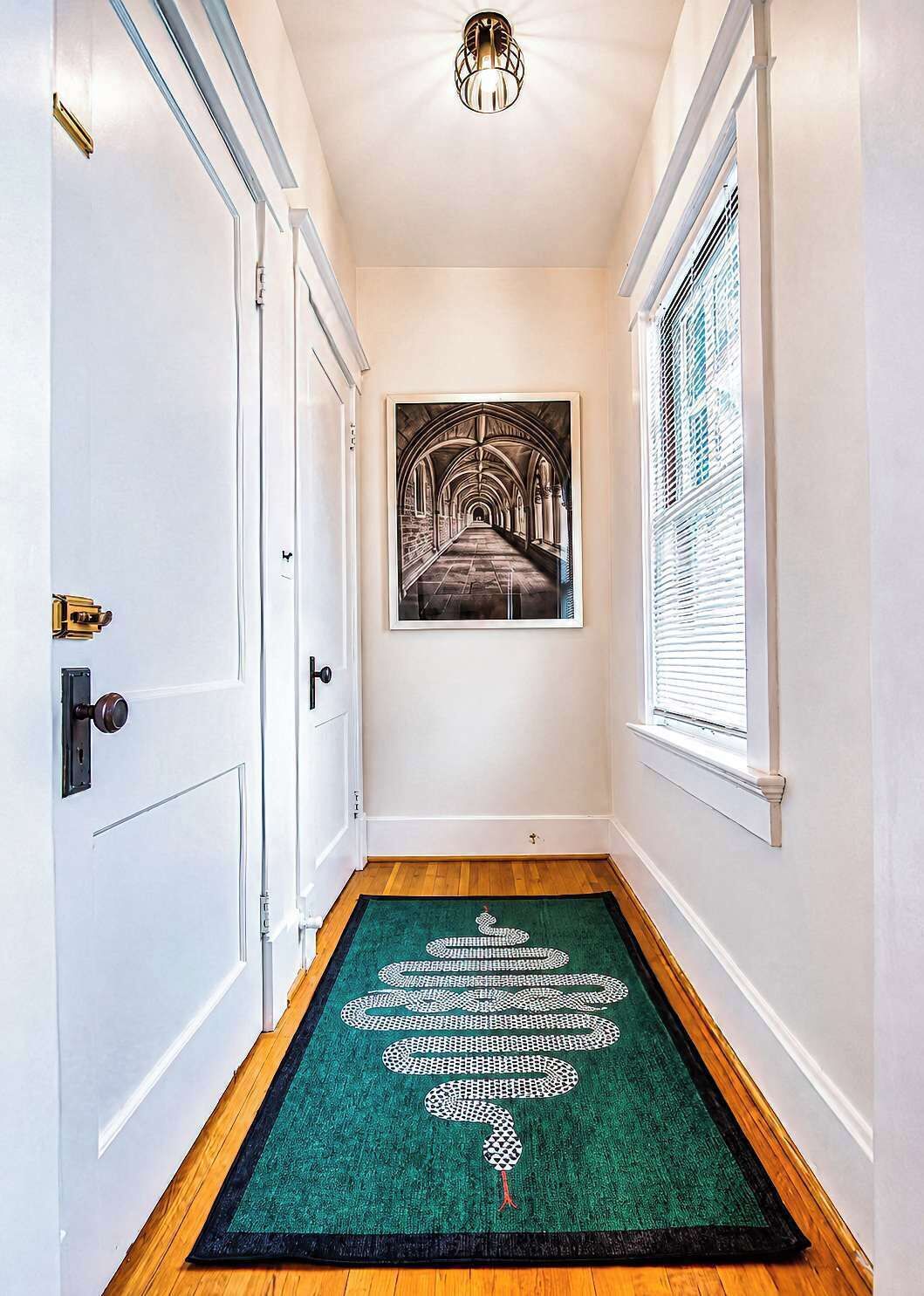 A hallway with a green carpet, a framed artwork, and a door with a brass handle.