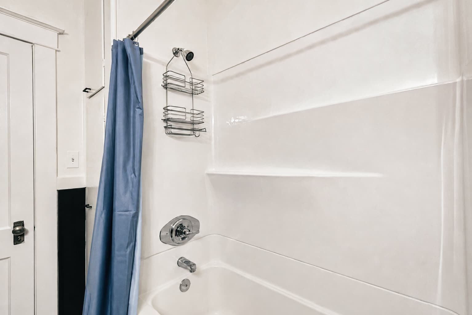 A bathroom with a bathtub, a shower curtain, and a metal towel rack.