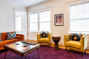 Un salon comprenant un canapé, deux fauteuils, une table basse et une batterie de percussion.