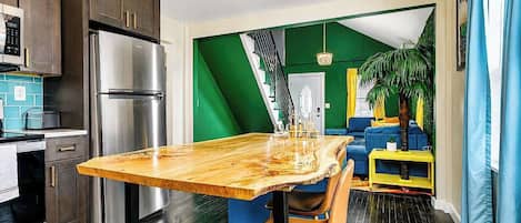 Une cuisine moderne avec une table à manger en bois, des appareils électroménagers en acier inoxydable et un mur d’accent vert.