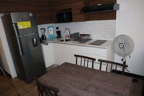 Eine kleine Küche mit Kühlschrank, Spüle und einem Ventilator.