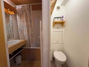 A bathroom with a shower, toilet, and a shelf with toiletries. - Appartement cosy 4 pers à Risoul - Résidence Altaïr (Risoul)
