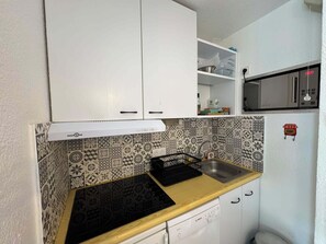A compact kitchen with white cabinets, a Bosch dishwasher, and patterned backsplash tiles. - Appartement cosy 4 pers à Risoul - Résidence Altaïr (Risoul)