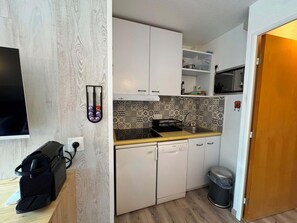 A compact kitchen with white cabinets, a black countertop, and patterned backsplash. - Appartement cosy 4 pers à Risoul - Résidence Altaïr (Risoul)