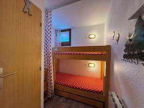A small, cozy room with a bunk bed, a window with a view, and a wall-mounted light fixture. - Appartement cosy 4 pers à Risoul - Résidence Altaïr (Risoul)