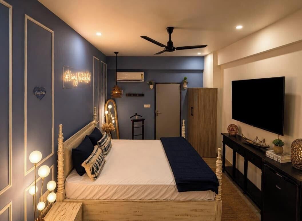 A bedroom with a bed, bedside lamps, a ceiling fan, a TV, and a wardrobe.