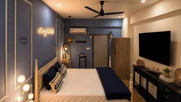 A bedroom with a bed, bedside lamps, a ceiling fan, a TV, and a wardrobe.