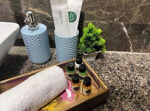 A bathroom counter with a dental kit, a tissue dispenser, a small plant, and a tray with various toiletries.