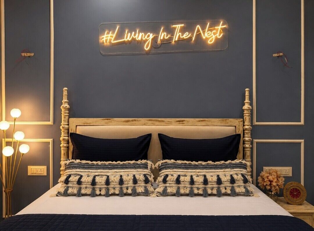 Quarto com cama, luminária de neon, abajures e mesa de cabeceira.