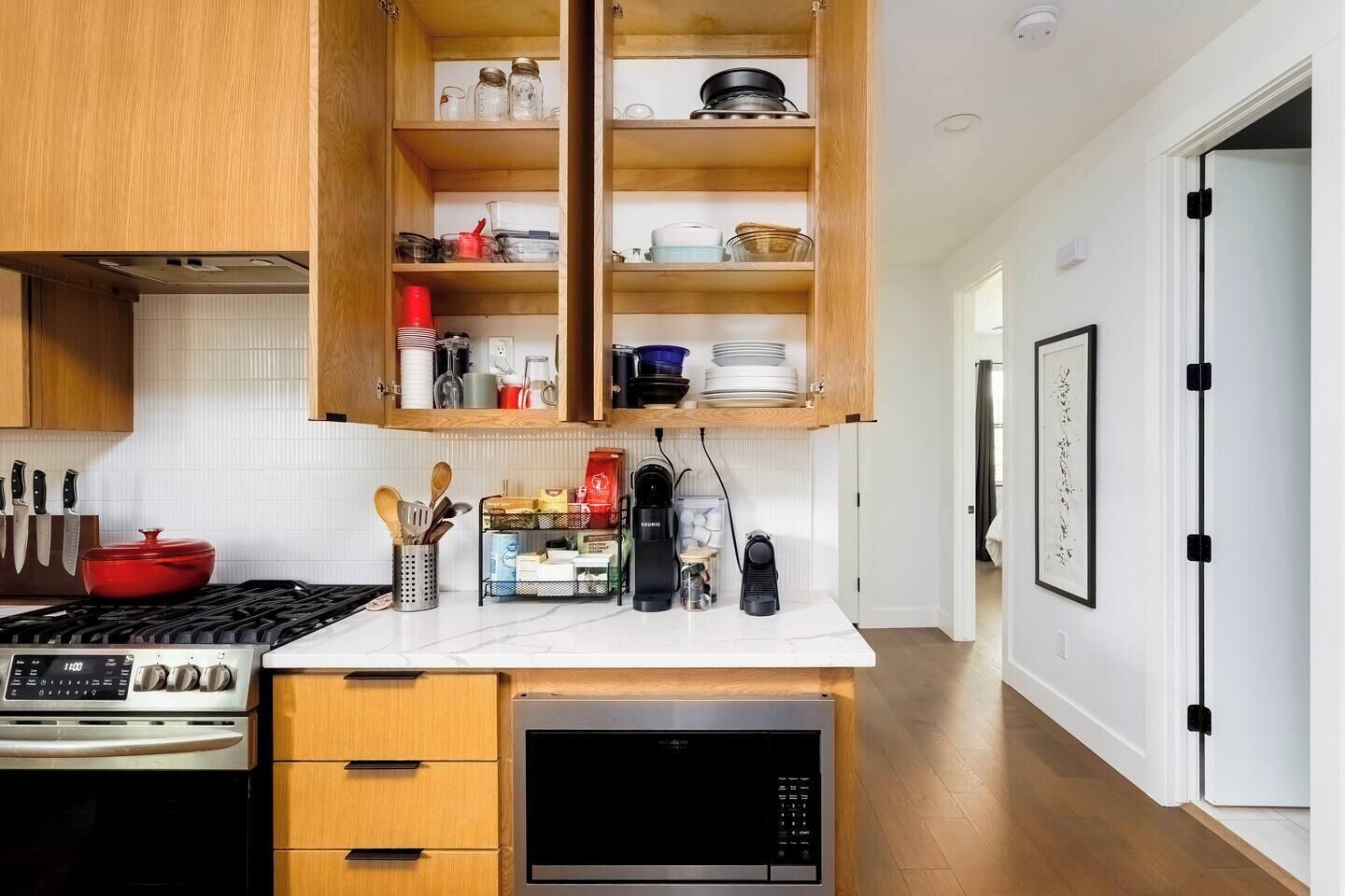A modern kitchen with wooden cabinets, a built-in stove, and a coffee maker.