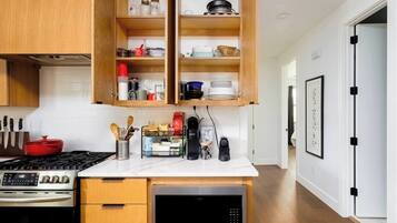 A modern kitchen with wooden cabinets, a built-in stove, and a coffee maker.