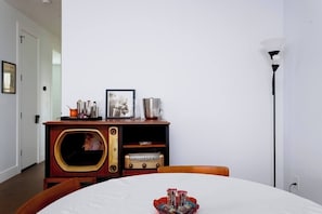 A room with a wooden cabinet, a framed picture, and a table with a white tablecloth. - New Modern Artist’s Studio - 2 units in 1 listing! (Oklahoma City)