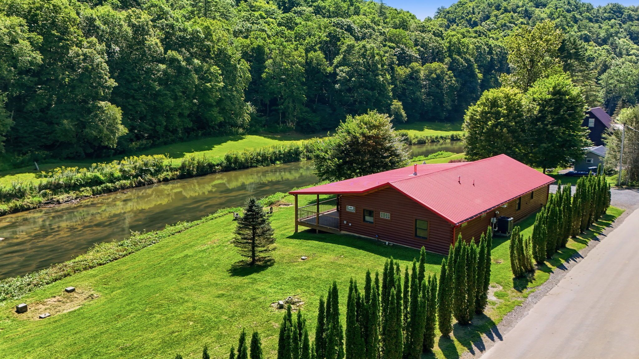 Eine Hütte mit rotem Dach, umgeben von üppigem Grün und einem Fluss.