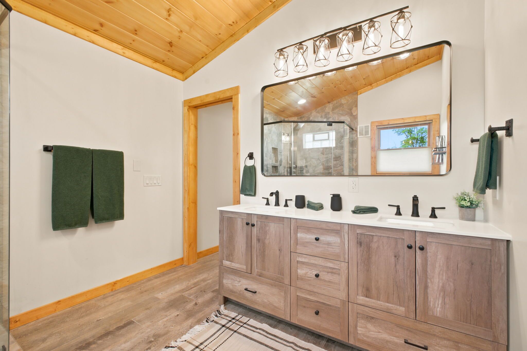 Une salle de bain avec un meuble-lavabo en bois, un grand miroir et un porte-serviettes.