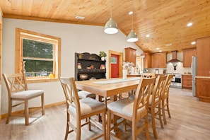 A wooden interior with a dining area, kitchen, and a red door. - Riverfront cabin with 3 bedrooms | 2 baths | fireplace | Wifi | fire pit. (Fleetwood)