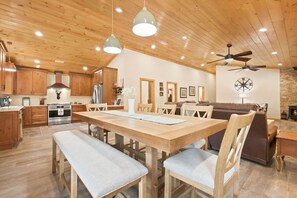 Eine moderne Küche mit Holzausbau, einem Edelstahlkühlschrank und einem Essbereich mit einem Holztisch und Bänken.