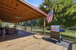 An outdoor deck with a grill, seating, and an American flag. - Riverfront cabin with 3 bedrooms | 2 baths | fireplace | Wifi | fire pit. (Fleetwood)