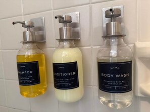 Tre flasker Lusspa personlig pleje produkter monteret på væggen.
