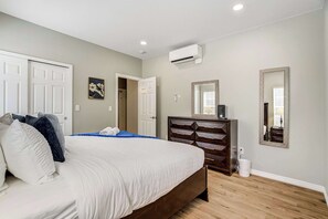 A bedroom with a bed, dresser, and two doors.