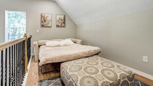 A bedroom with a bed, a bench, a window, and two wall-mounted artworks. - Ponderosa Glade! Hot Tub & Forest Views by USAFA (Monument)