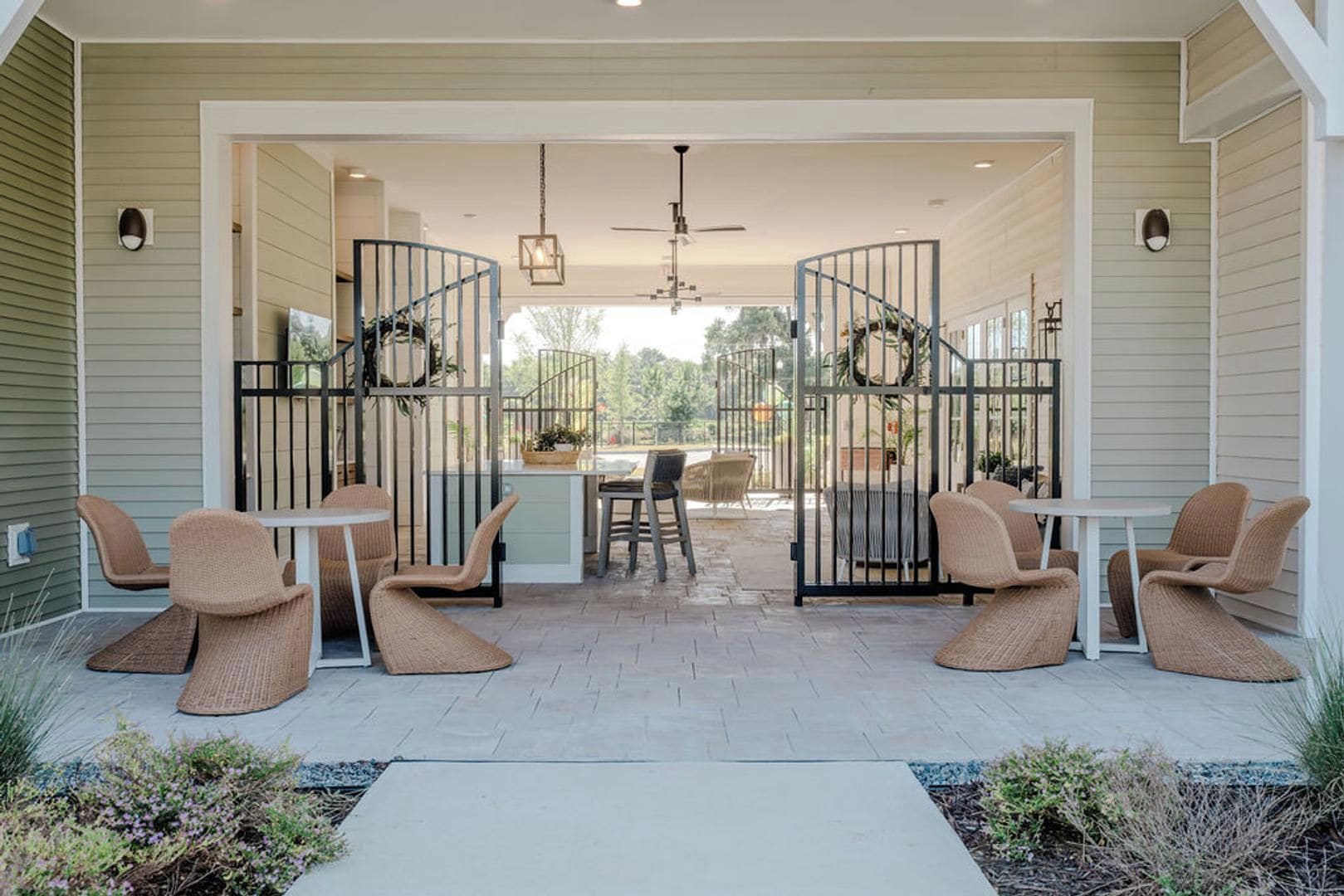 A covered patio with wicker furniture, a central table, and a view of the outdoors.