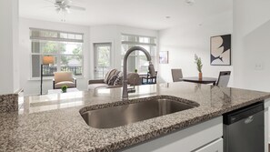 Cozinha moderna com bancada de granito, pia de aço inoxidável e lava-louças.