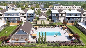 Un complejo residencial con piscina central, varias casas y un césped bien cuidado.