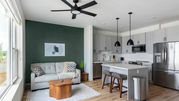 A modern kitchen with a central island, stainless steel appliances, and a ceiling fan.