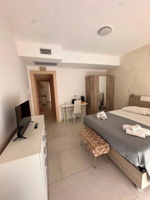 Ein modernes Hotelzimmer mit Bett, Schreibtisch, Stuhl und Fernseher.