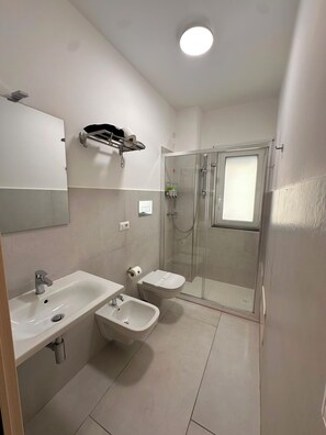 Ein Badezimmer mit Waschbecken, Bidet, Toilette und einer Duschkabine.