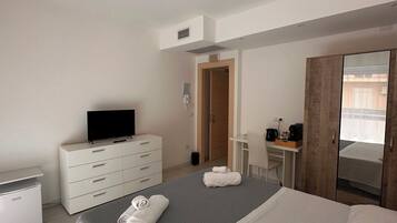 Ein Hotelzimmer mit einem Bett, einem Fernseher, einem Schminktischchen, einem Schreibtisch und einem Kleiderschrank.