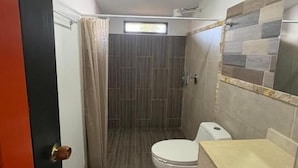 A compact bathroom with a toilet, sink, and shower area. - Finca Cacique Amarillo (Circasia)