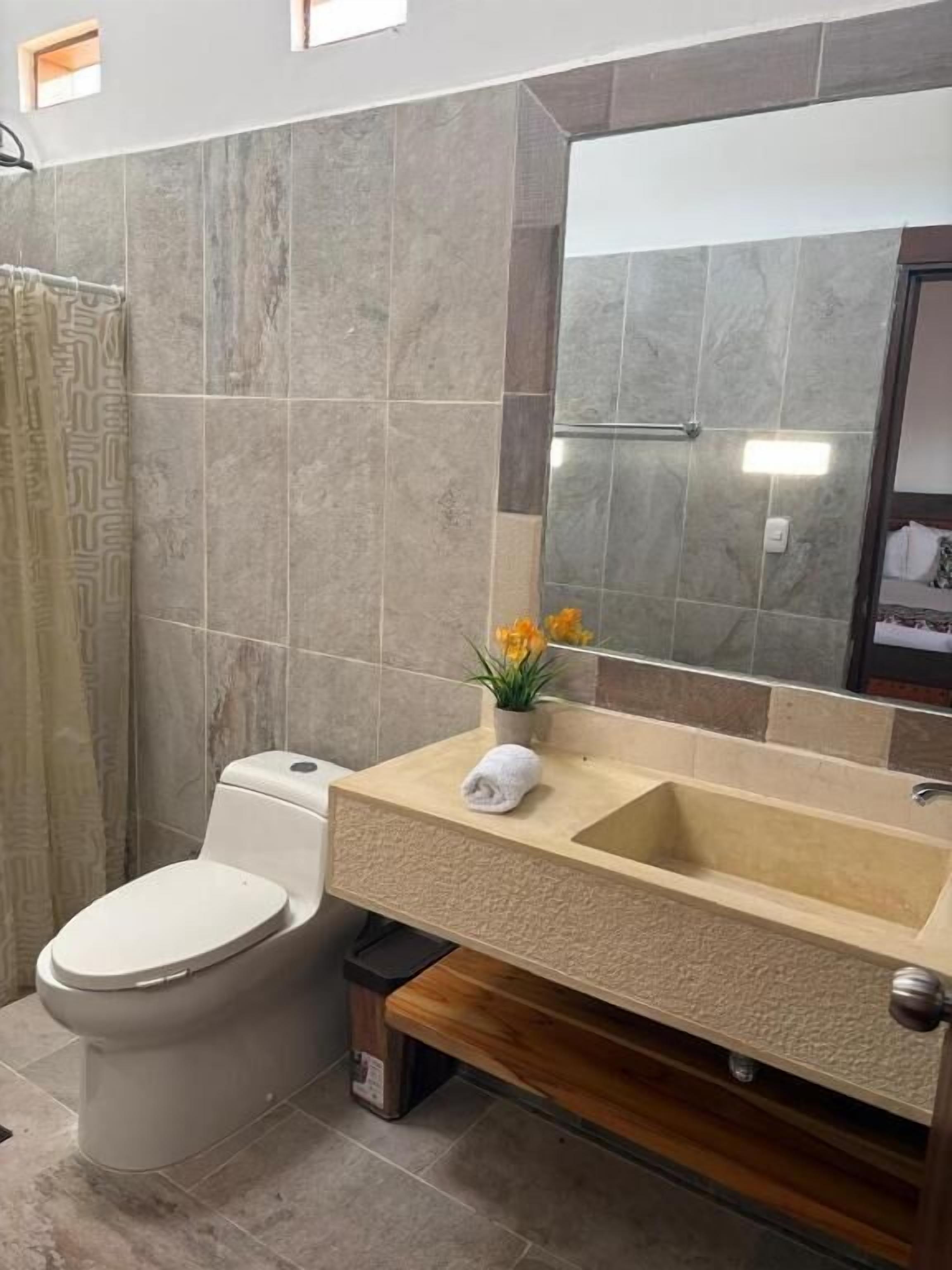 Un baño con inodoro, lavamanos y espejo.