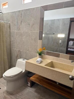 A bathroom with a toilet, sink, and mirror. - Finca Cacique Amarillo (Circasia)