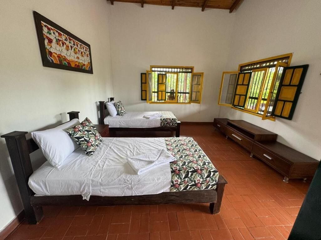 Una habitación con dos camas, un banco y un armario de madera.