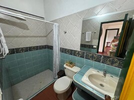 Un baño con inodoro, lavabo y zona de ducha.