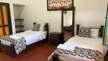 Una habitación de hotel con dos camas, un armario, un espejo y una obra de arte colorida en la pared.