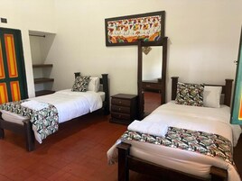 Una habitación de hotel con dos camas, un armario, un espejo y una obra de arte colorida en la pared.