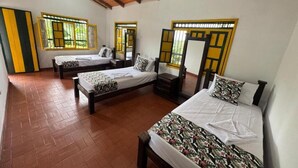 A room with three beds, wooden beams on the ceiling, and large windows with yellow frames. - Finca Cacique Amarillo (Circasia)
