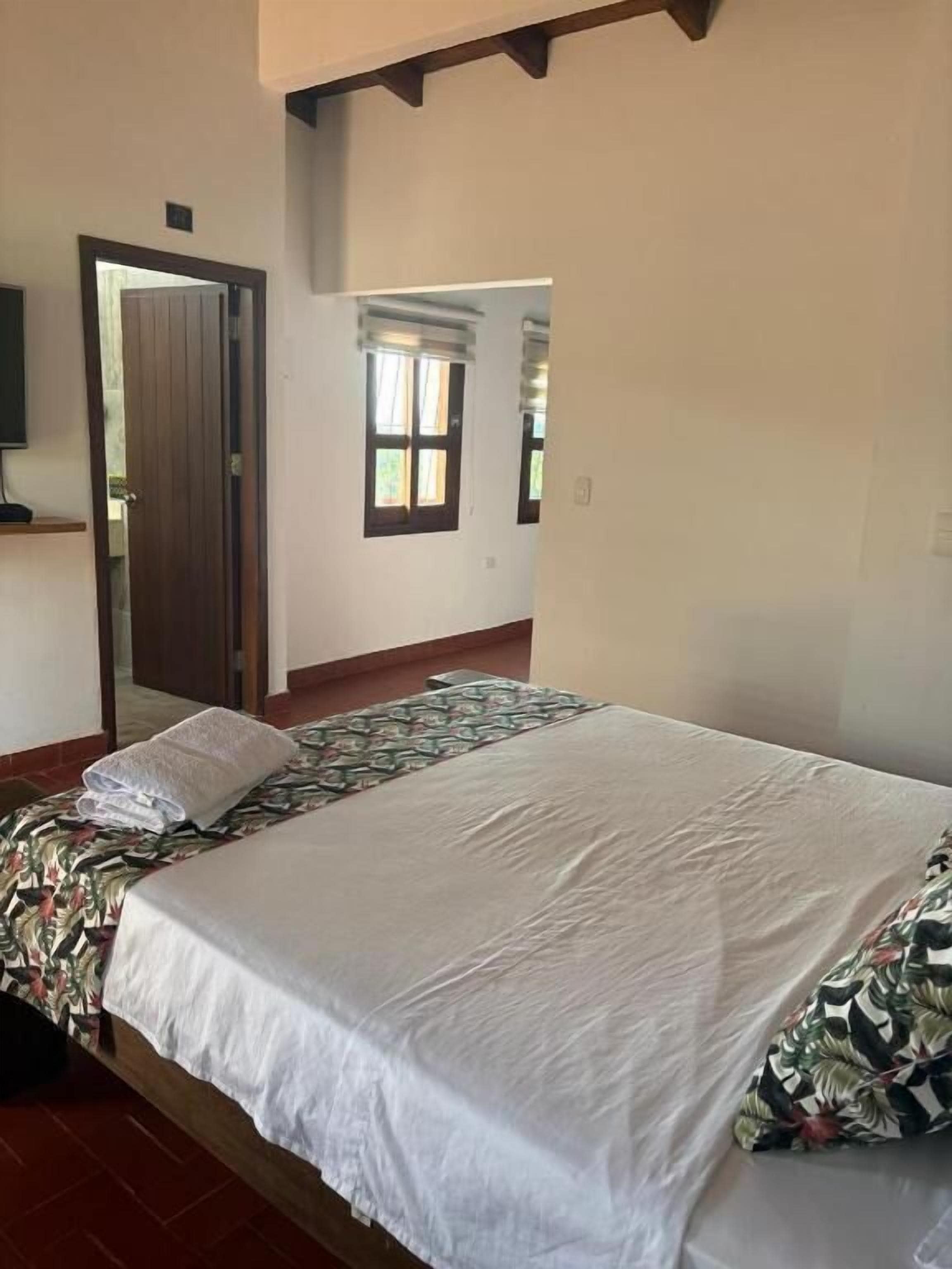 Un dormitorio con cama, puerta y ventana.