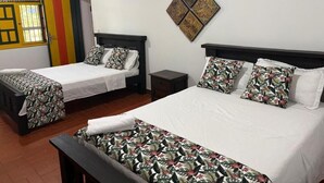 A hotel room with two beds, a small table, and a wall-mounted artwork. - Finca Cacique Amarillo (Circasia)