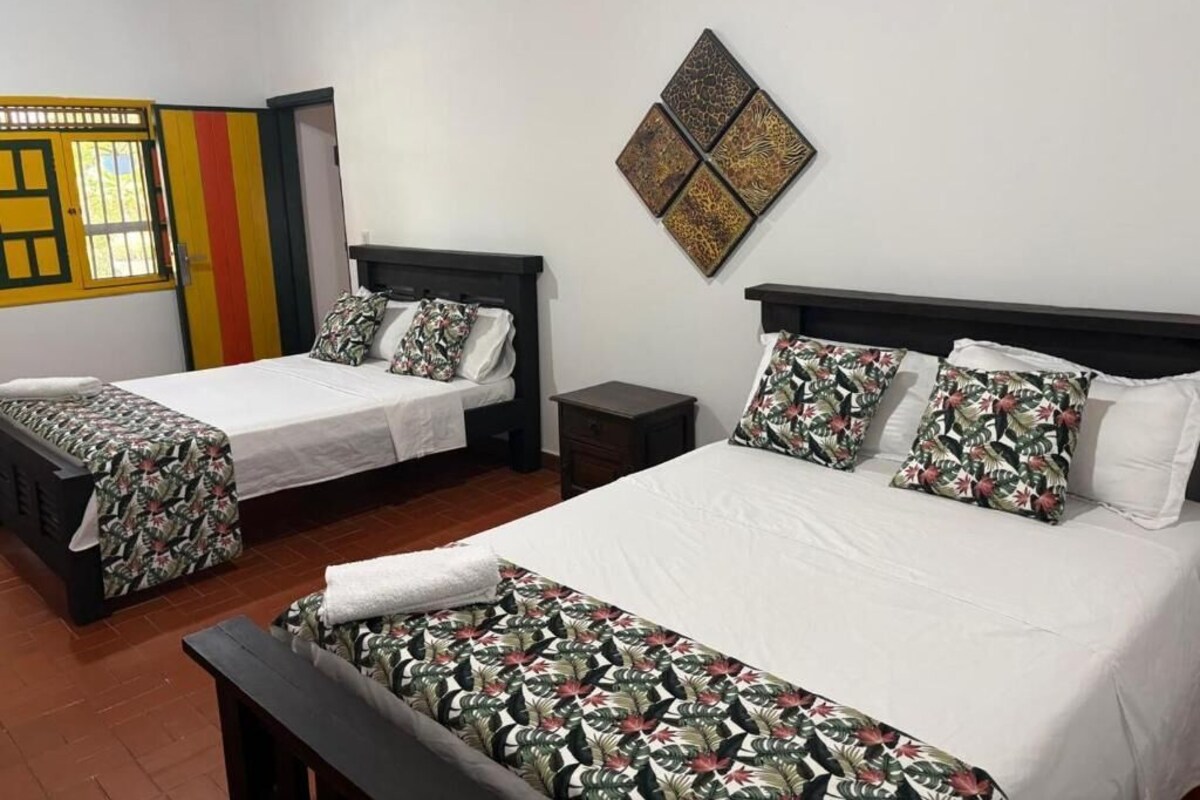 Ein Hotelzimmer mit zwei Betten, einem kleinen Tisch und einem an der Wand hängenden Kunstwerk.