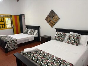 Ein Hotelzimmer mit zwei Betten, einem kleinen Tisch und einem an der Wand hängenden Kunstwerk.