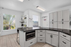 Una cucina moderna con mobili bianchi, un piano di lavoro nero e un forno integrato.