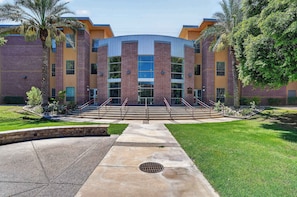 A multi-story building with a central atrium, surrounded by a well-maintained lawn and palm trees. - The Nest | Cozy Comfort near DT Tempe and UAT (Tempe)