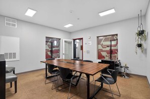 A conference room with a wooden table, black chairs, a whiteboard, and a door with a red frame. - The Nest | Cozy Comfort near DT Tempe and UAT (Tempe)
