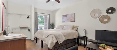 A bedroom with a bed, bedside table, TV, and a ceiling fan.
