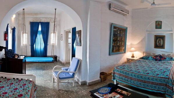 Una habitación con cama, una silla, un columpio y una mesita.